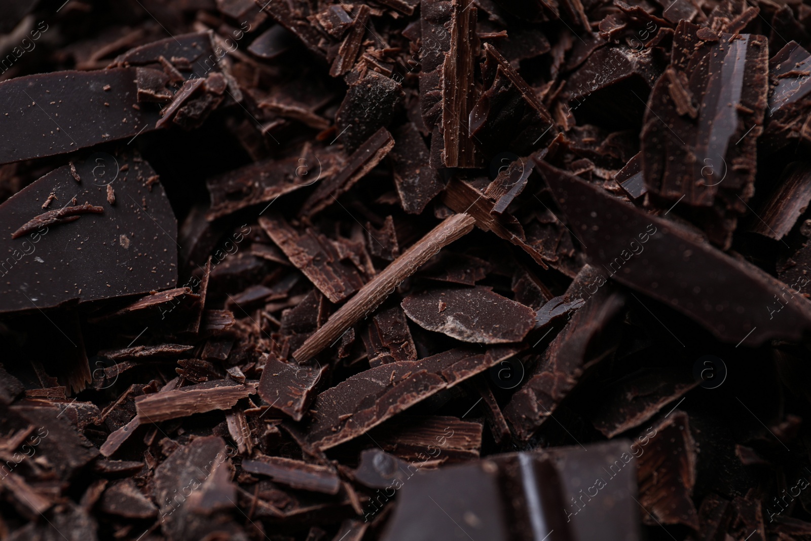 Photo of Tasty crushed dark chocolate as background, closeup