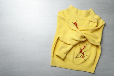 Yellow warm sweater on light grey table, top view. Space for text
