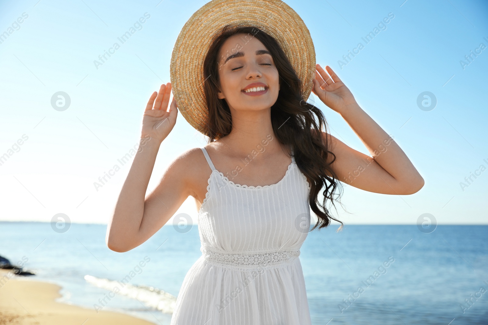 Photo of Happy young woman with beach hat near sea