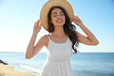 Happy young woman with beach hat near sea