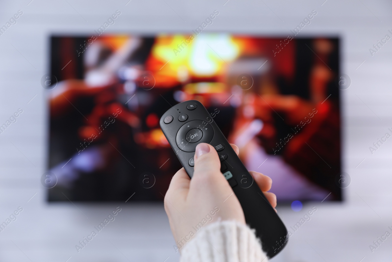 Photo of Woman with remote control watching TV at home, closeup