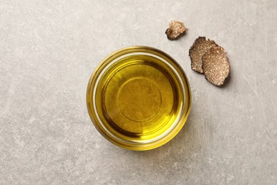 Photo of Bowl of truffle oil on light grey table, flat lay