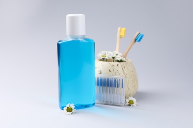 Photo of Composition with fresh mouthwash in bottle, toothbrushes and interdental brushes on grey background
