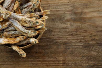 Photo of Delicious dried anchovies on wooden table. Space for text