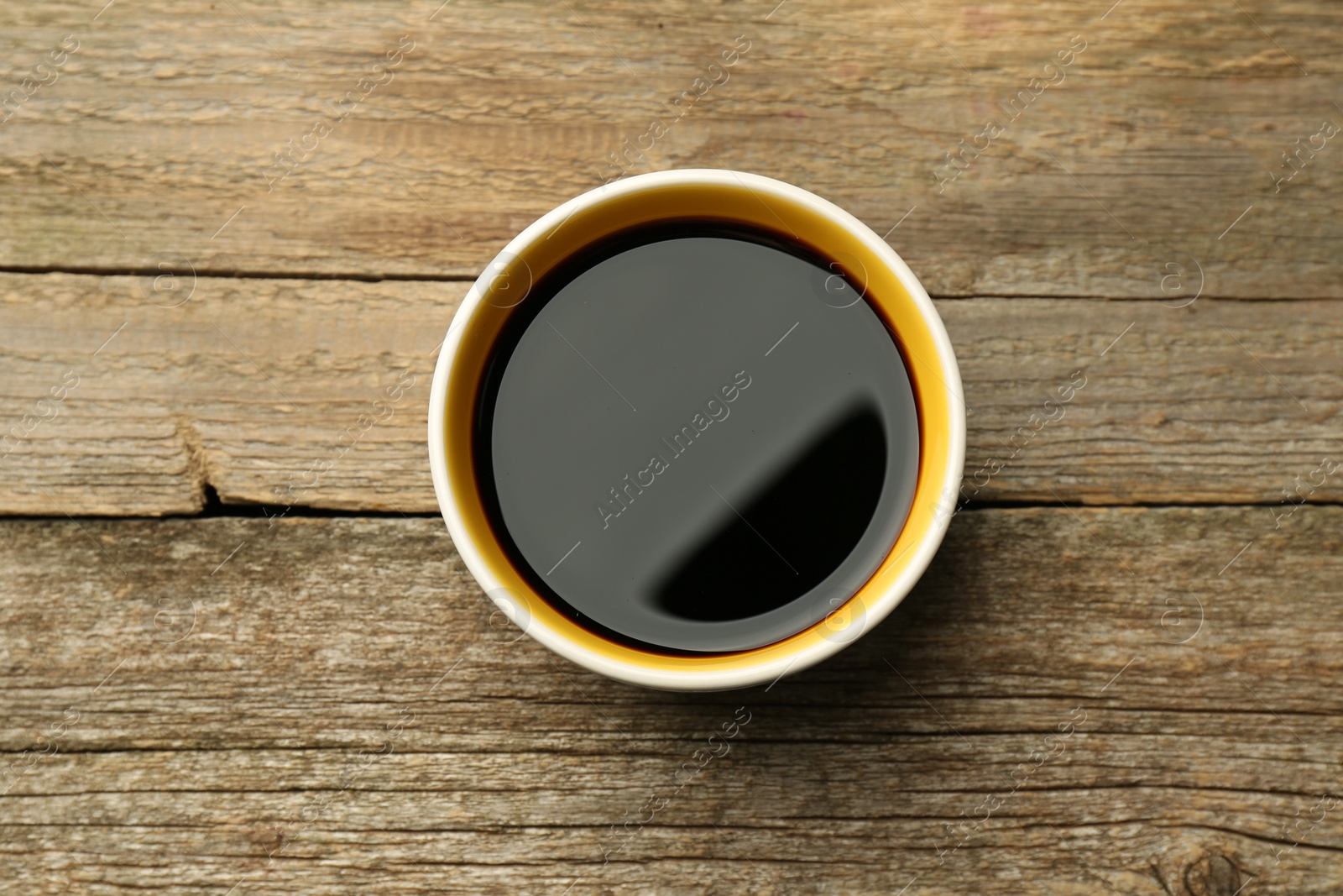 Photo of Soy sauce in bowl on wooden table, top view