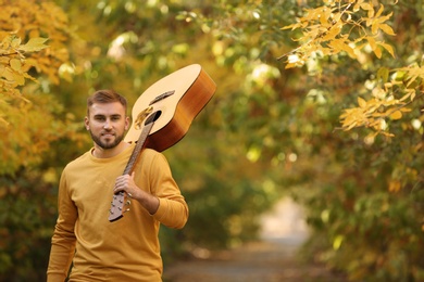 Photo of Young man with guitar in autumn park