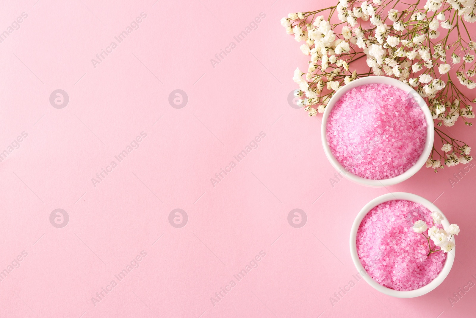 Photo of Aromatic sea salt and beautiful flowers on pink background, flat lay. Space for text