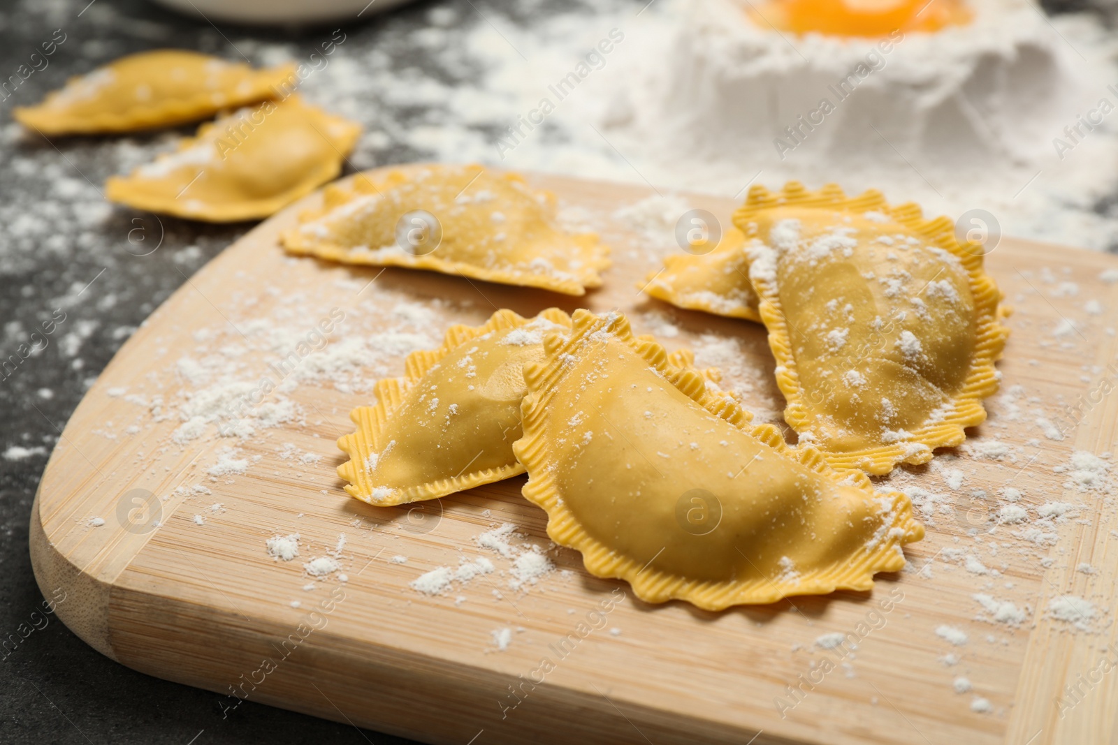 Photo of Raw ravioli on wooden board, closeup view. Italian pasta