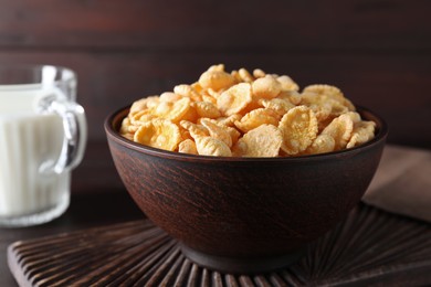Photo of Bowl of tasty crispy corn flakes on wooden board, closeup