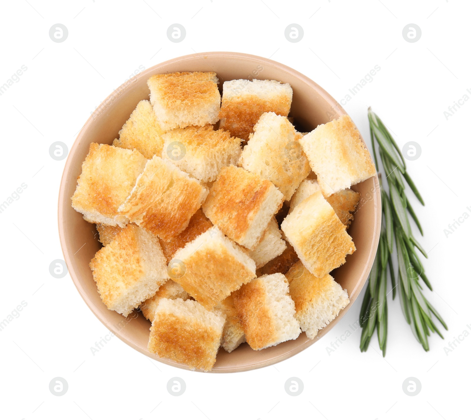 Photo of Delicious crispy croutons in bowl and rosemary on white background, top view