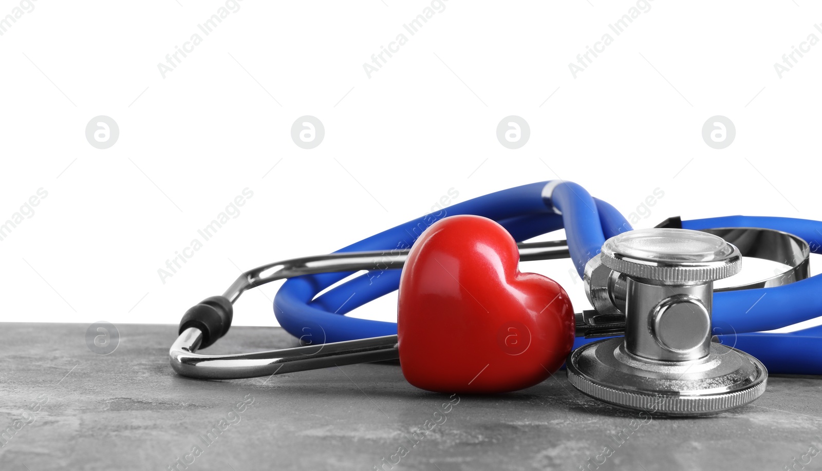 Photo of Stethoscope and red heart on grey table against white background