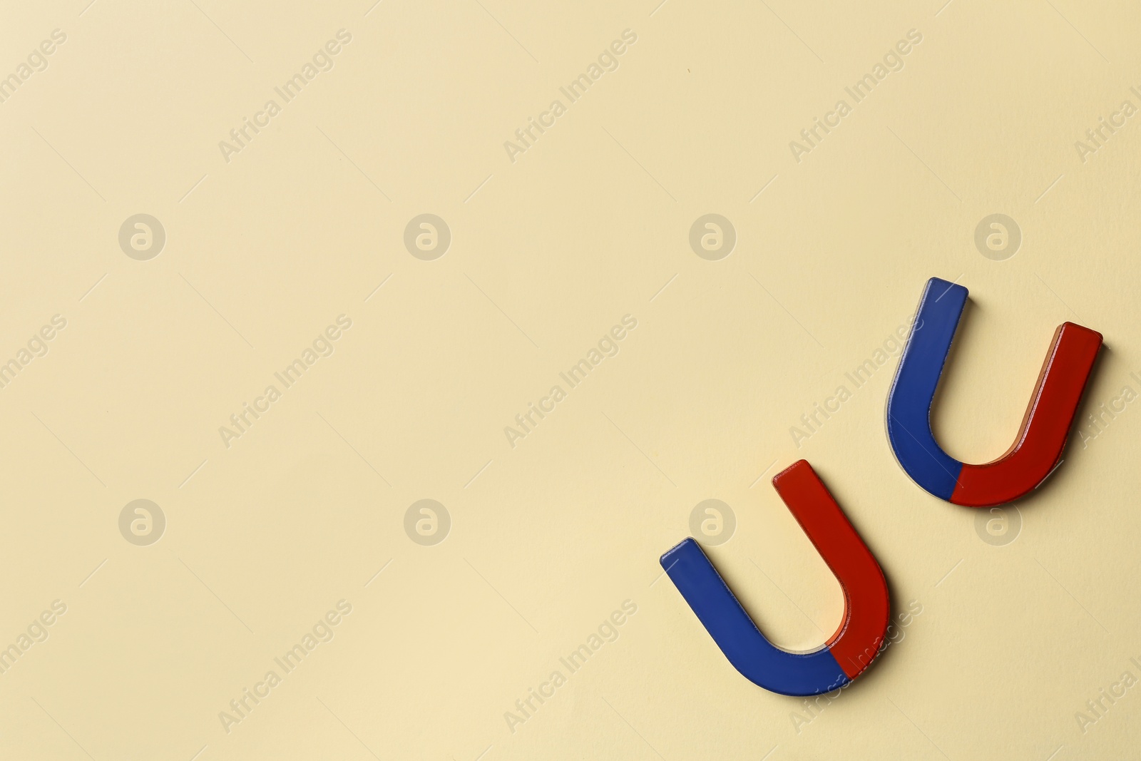 Photo of Red and blue horseshoe magnets on light beige background, flat lay. Space for text