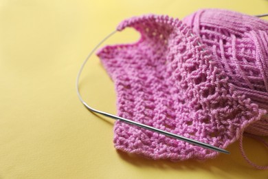Photo of Pink knitting, yarn and needles on yellow background, closeup. Space for text