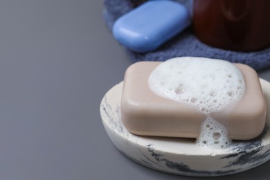 Dish with soap bar and fluffy foam on grey background, space for text