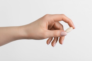 Woman holding vitamin pill on white background, closeup. Health supplement