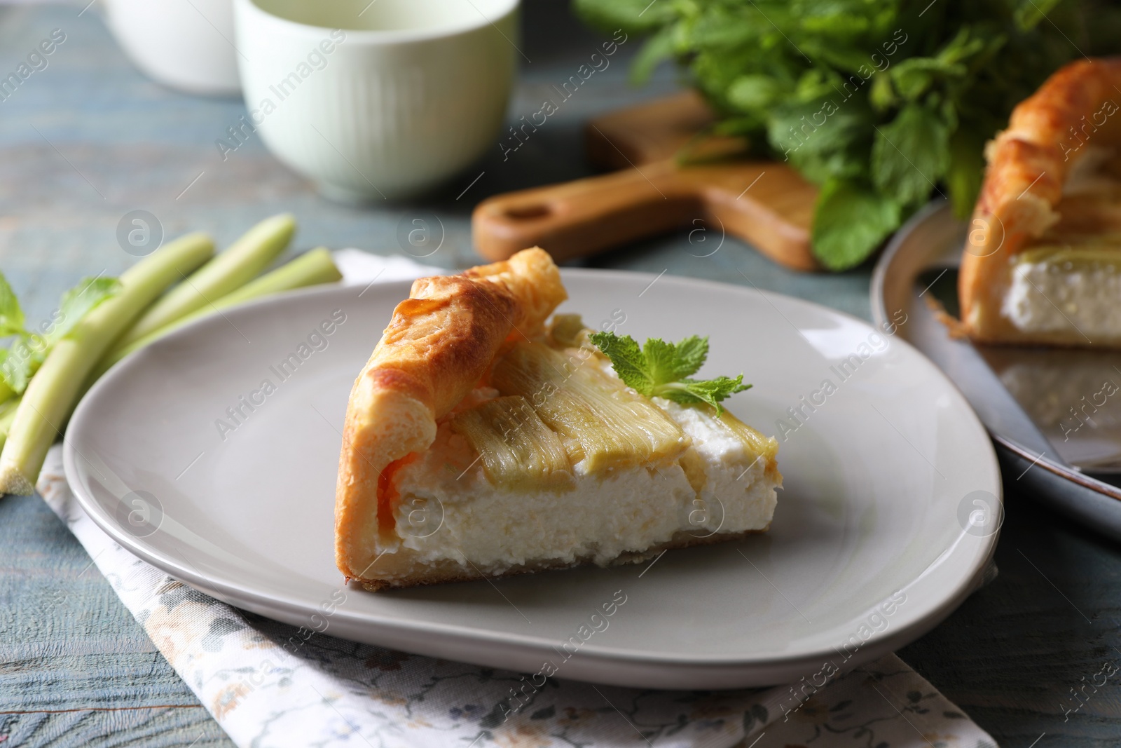 Photo of Freshly baked rhubarb pie with cream cheese and stalks on grey wooden table, closeup