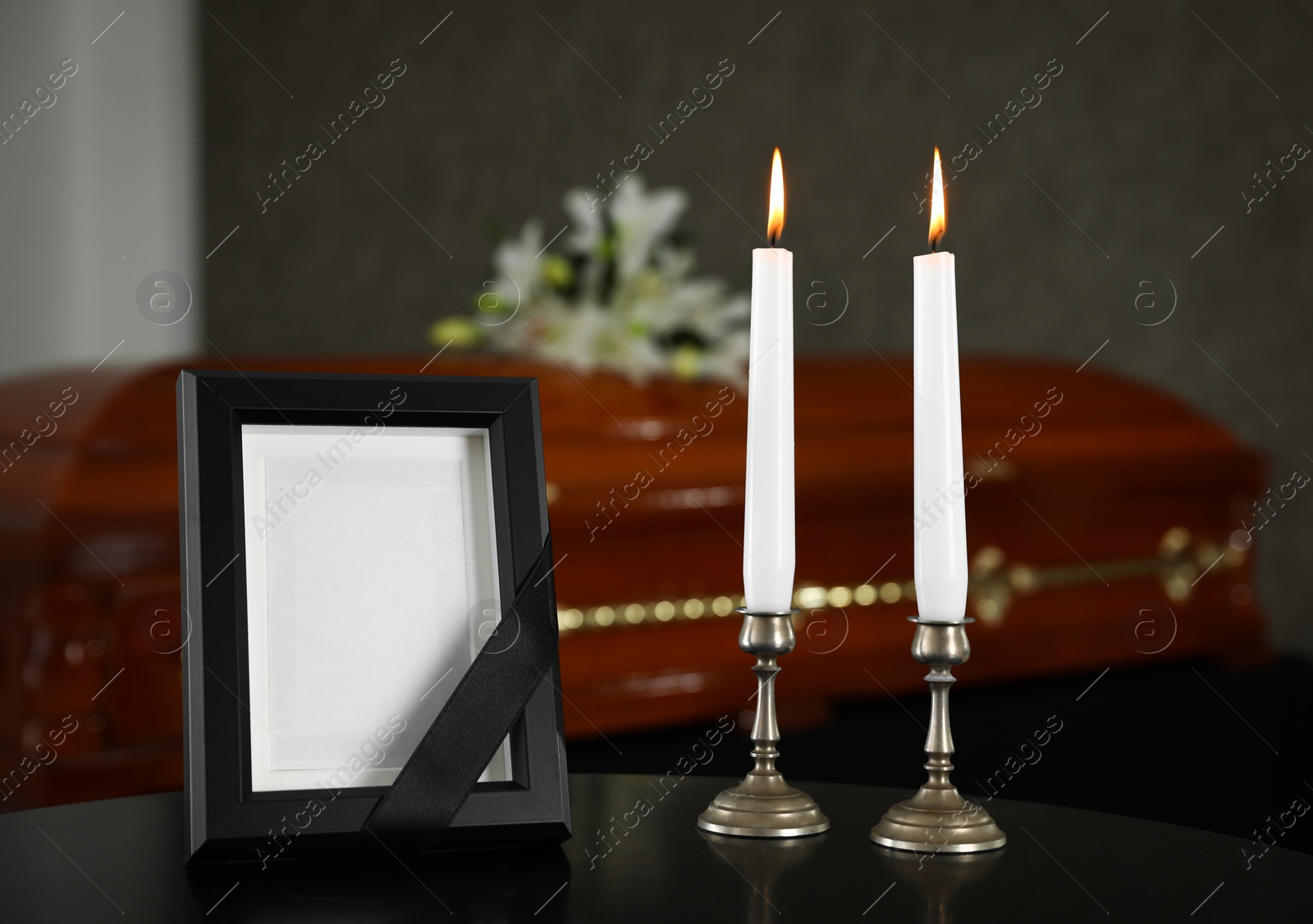 Photo of Black photo frame with burning candles on table in funeral home