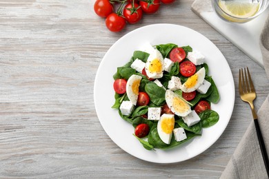 Photo of Delicious salad with boiled eggs, feta cheese and tomatoes served on wooden table, flat lay. Space for text