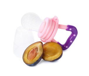 Photo of Empty nibbler and cut plum on white background. Baby feeder