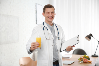 Nutritionist with glass of juice and clipboard in office