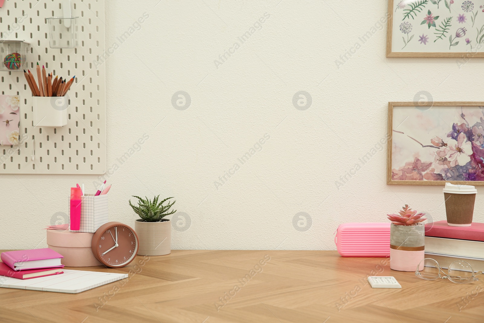 Photo of Stylish workplace with stationery on wooden desk near white wall. Interior design