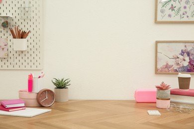 Stylish workplace with stationery on wooden desk near white wall. Interior design