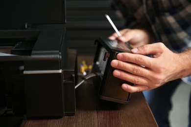 Professional repairman fixing modern printer indoors, closeup