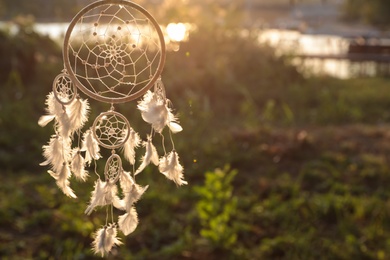 Photo of Beautiful handmade dream catcher outdoors. Space for text