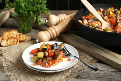 Photo of Delicious ratatouille served with bread on wooden table