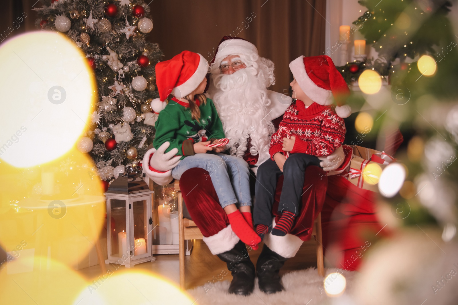 Photo of Santa Claus and children in room decorated for Christmas