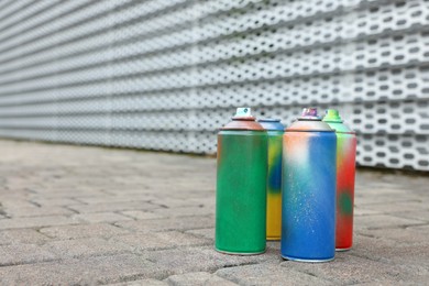 Used cans of spray paints on pavement, space for text