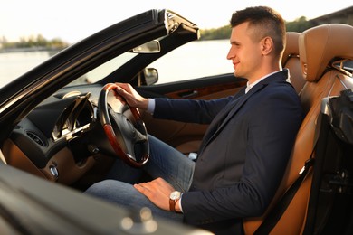 Photo of Young businessman in luxury convertible car outdoors