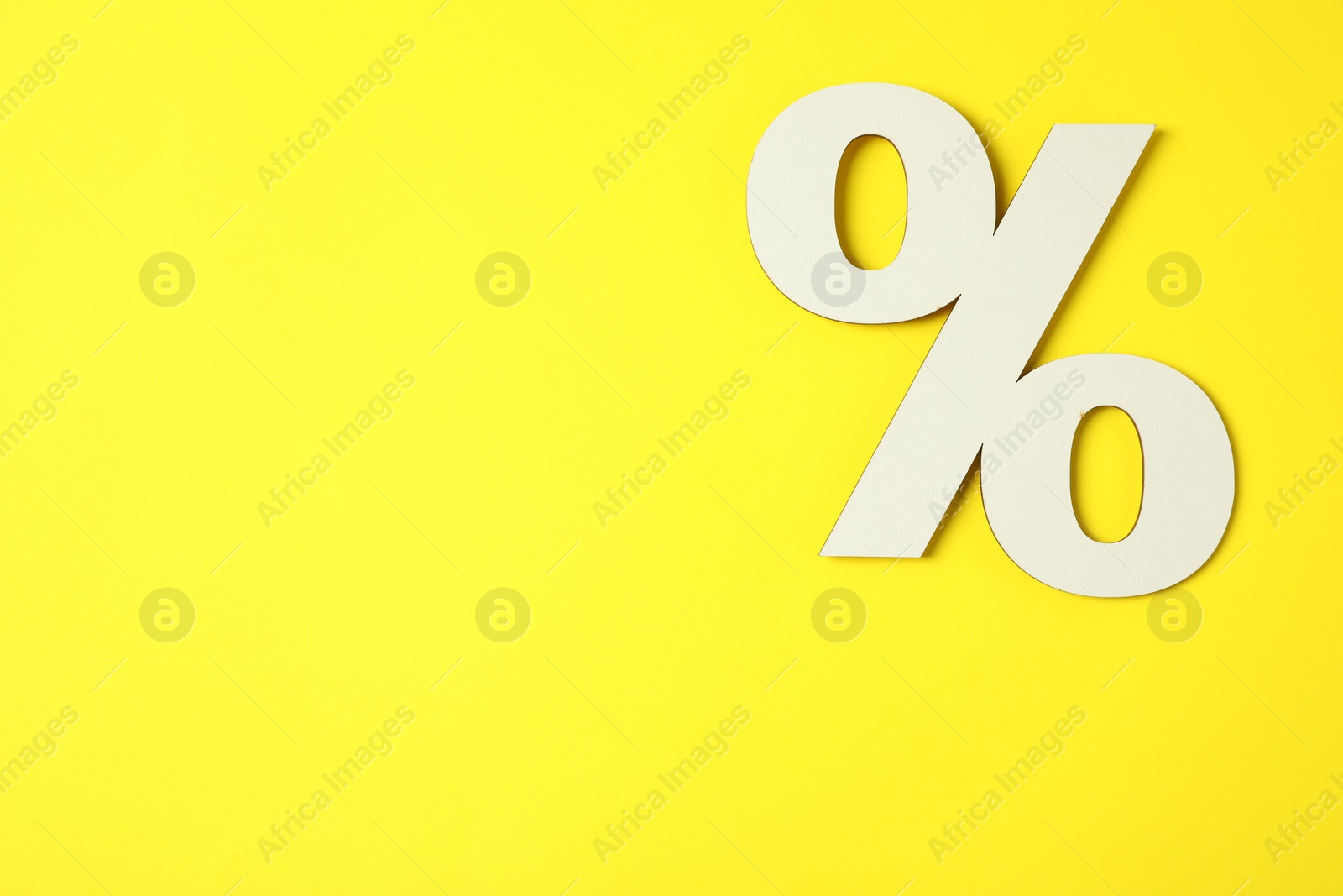 Photo of White percent sign on yellow background, top view. Space for text