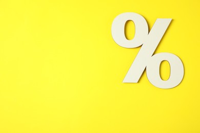 Photo of White percent sign on yellow background, top view. Space for text