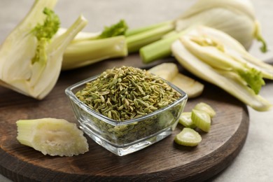 Photo of Fennel seeds in bowl and fresh vegetables on table, closeup