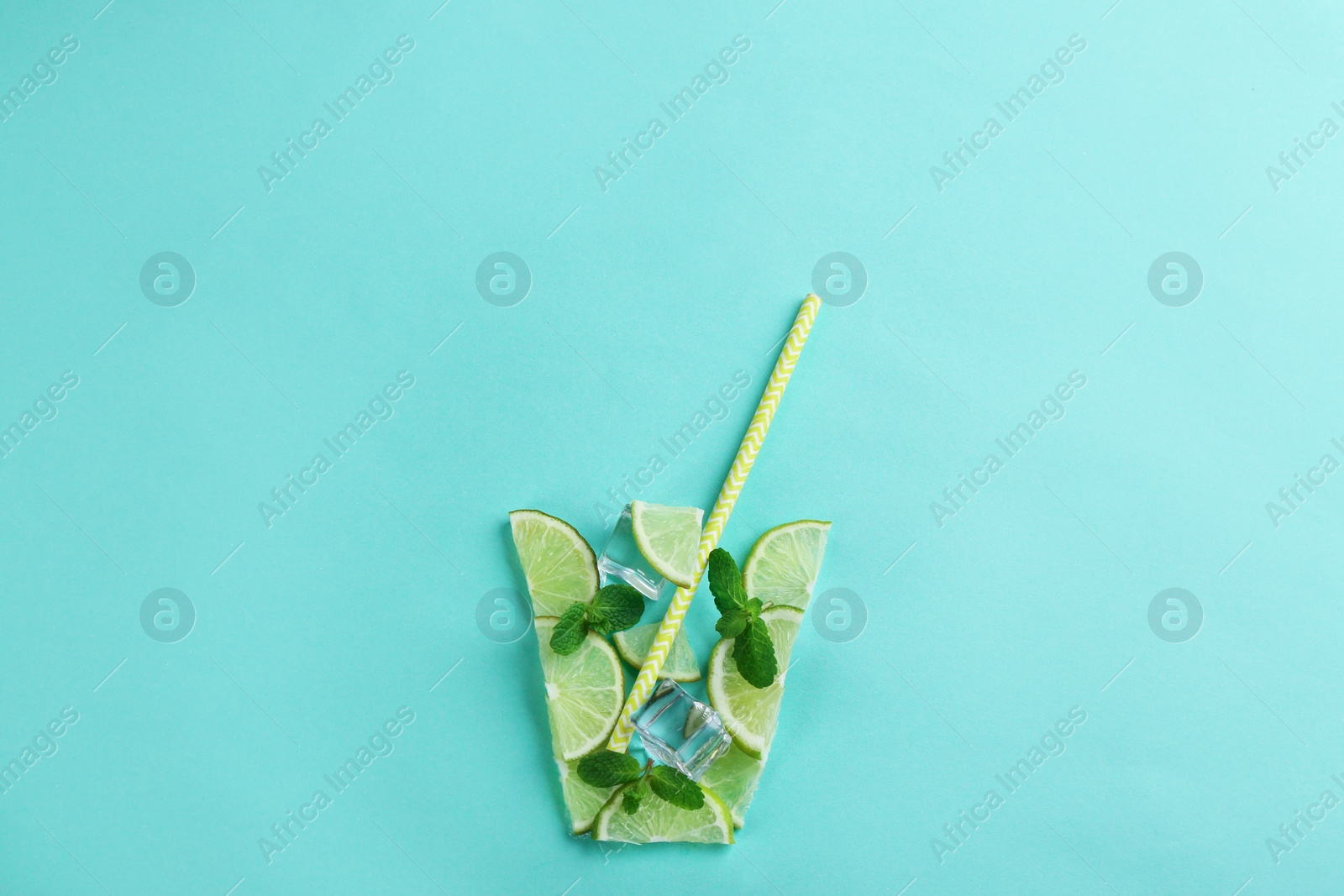 Photo of Creative lemonade layout with lemon slices, mint and ice on turquoise background, top view