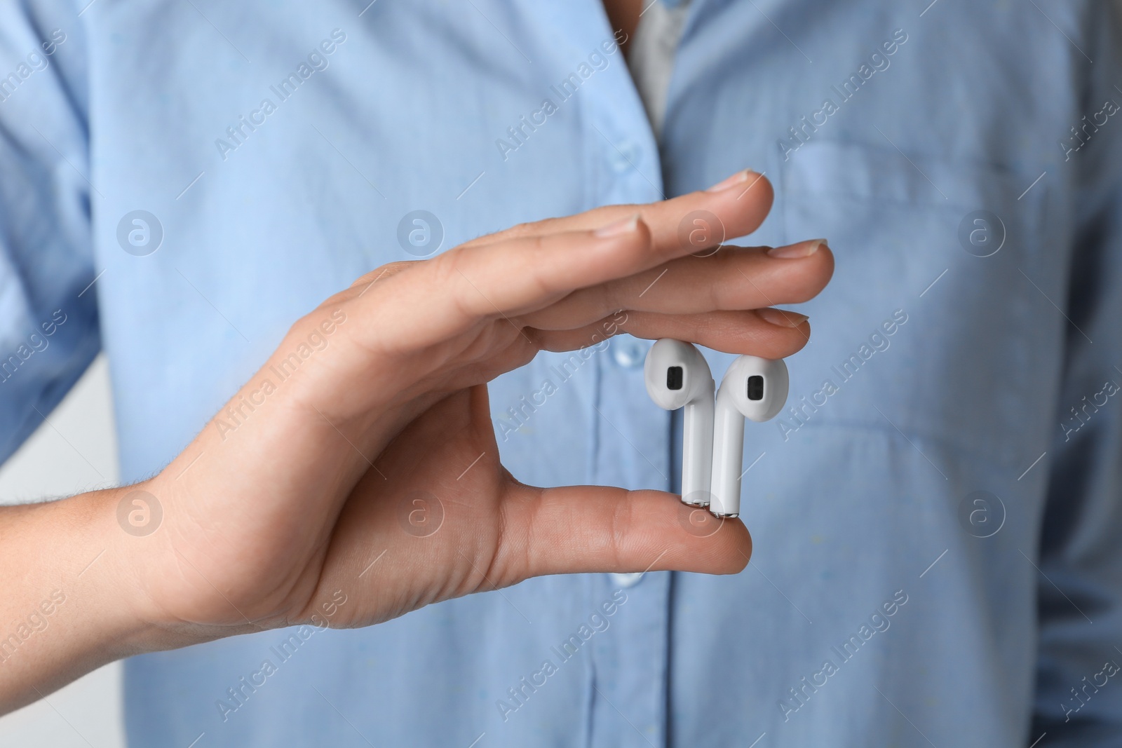 Photo of Woman holding pair of wireless earphones, closeup