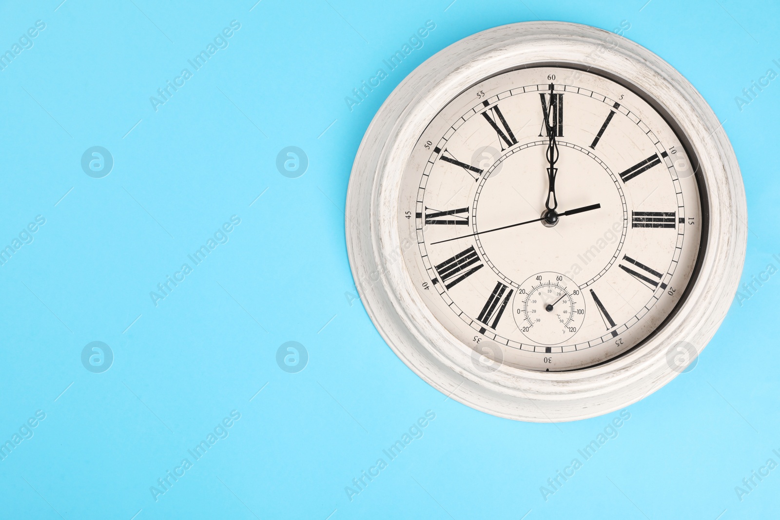 Photo of Stylish vintage wall clock on turquoise background, top view with space for text