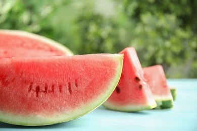 Photo of Tasty ripe cut watermelon on light blue wooden table