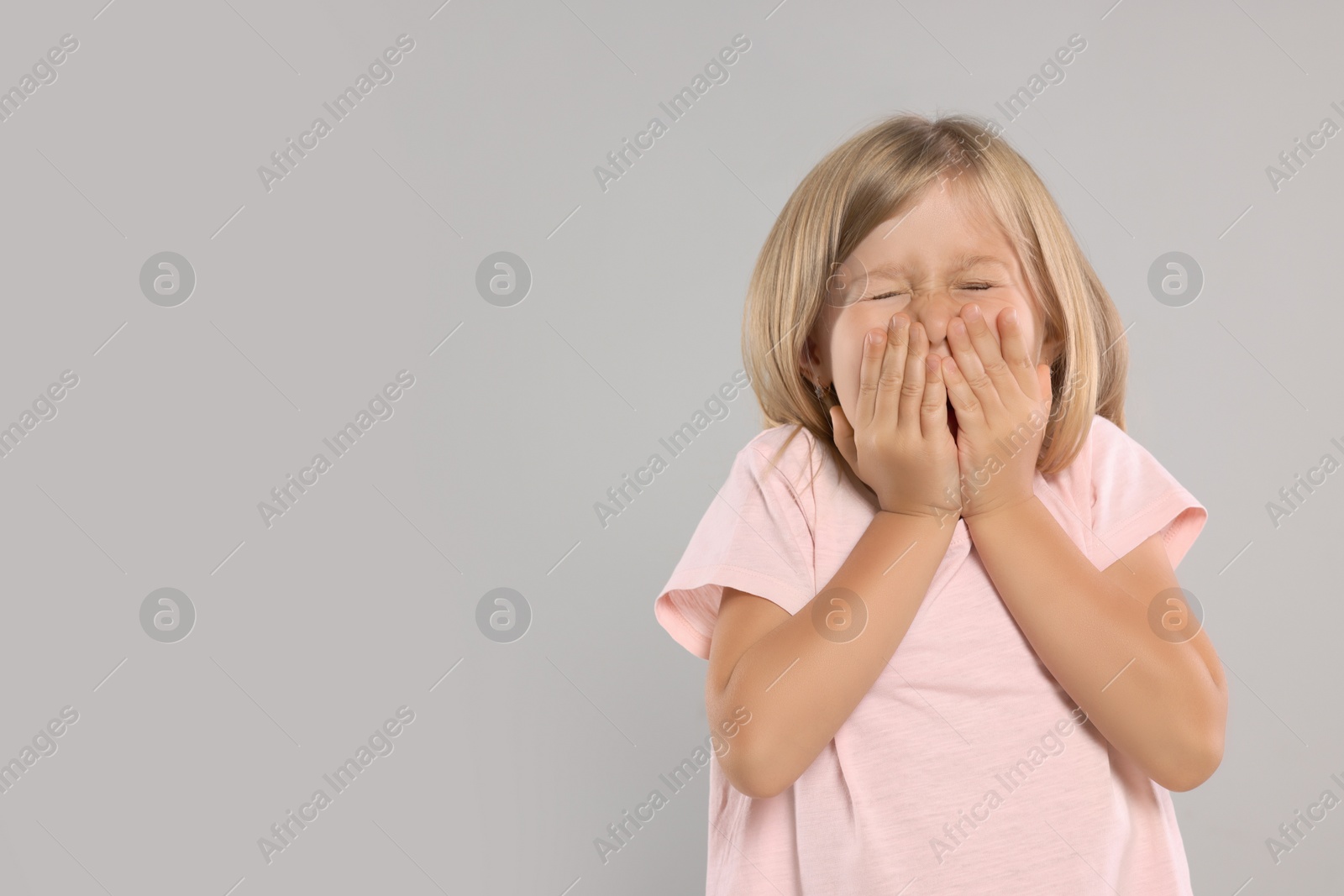 Photo of Suffering from allergy. Little girl sneezing on light gray background, space for text