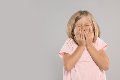 Photo of Suffering from allergy. Little girl sneezing on light gray background, space for text