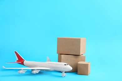 Photo of Airplane model and carton boxes on light blue background. Courier service