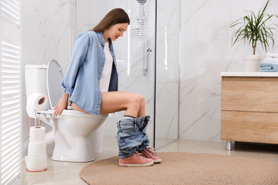 Photo of Woman suffering from hemorrhoid on toilet bowl in rest room