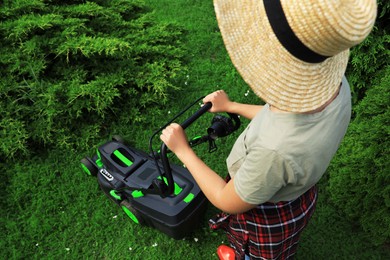 Photo of Woman cutting grass with lawn mower in garden