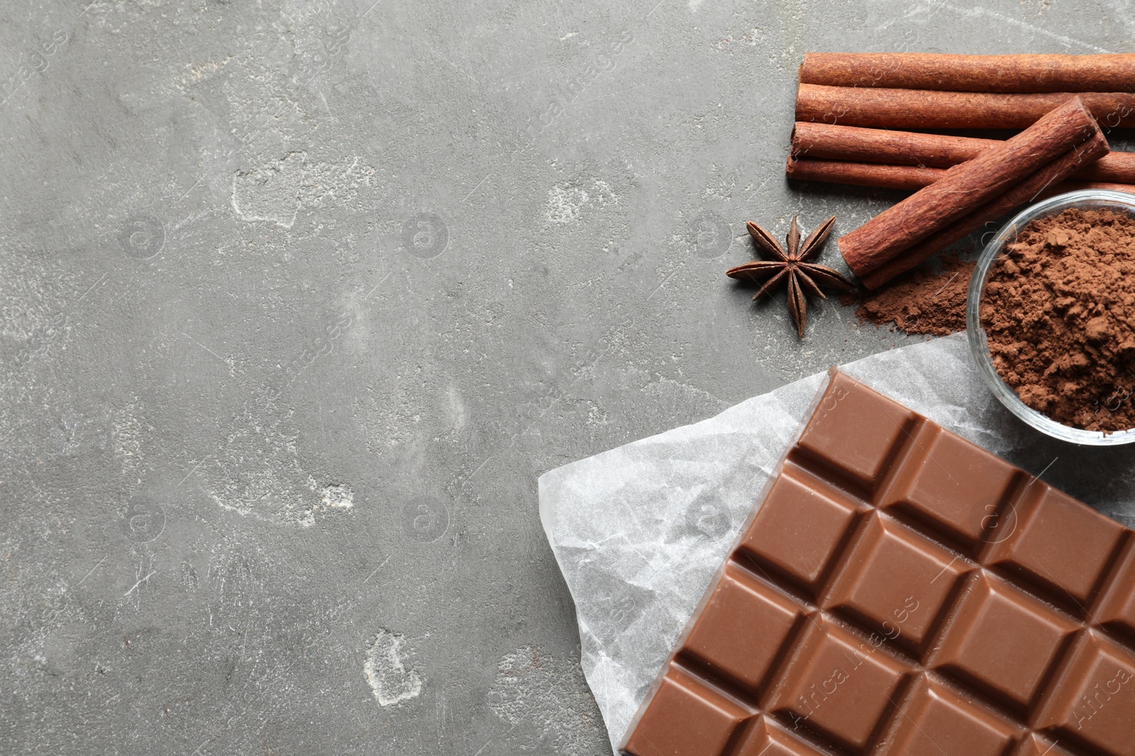 Photo of Chocolate bar and cocoa powder on grey background, flat lay. Space for text