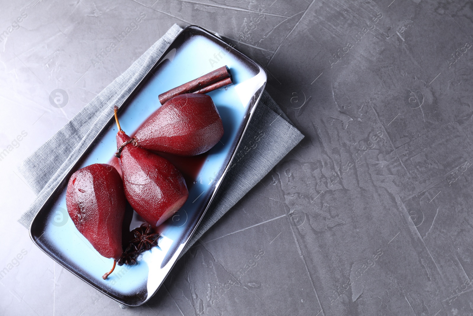 Photo of Tasty red wine poached pears and spices on grey table, top view. Space for text