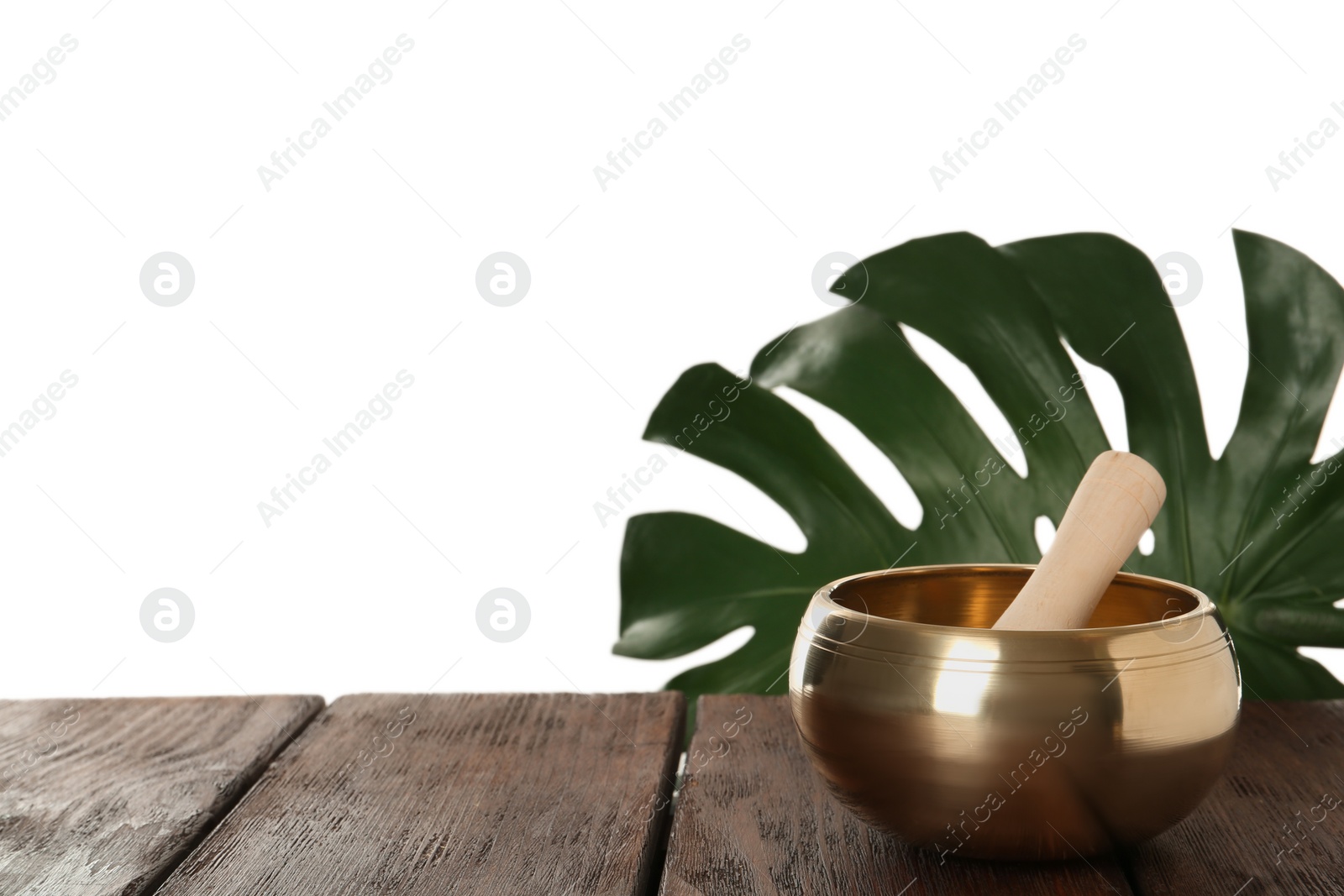 Photo of Golden singing bowl and mallet on wooden table against white background, space for text