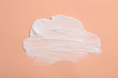 Photo of Sample of face cream on coral background, top view