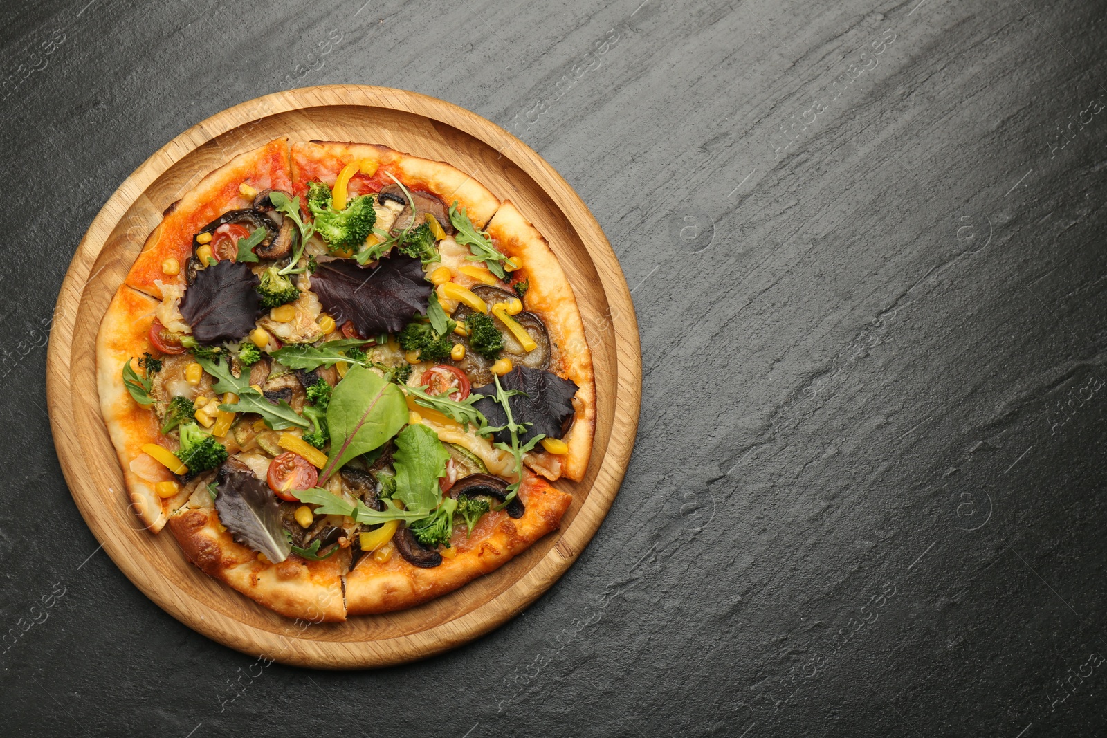 Photo of Delicious vegetarian pizza with mushrooms, vegetables and greens on black table, top view. Space for text