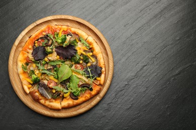 Photo of Delicious vegetarian pizza with mushrooms, vegetables and greens on black table, top view. Space for text